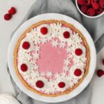 overhead of raspberry pie with whipped cream and fresh raspberries