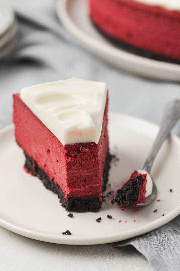 close up of red velvet cheesecake with a fork taking a bite out