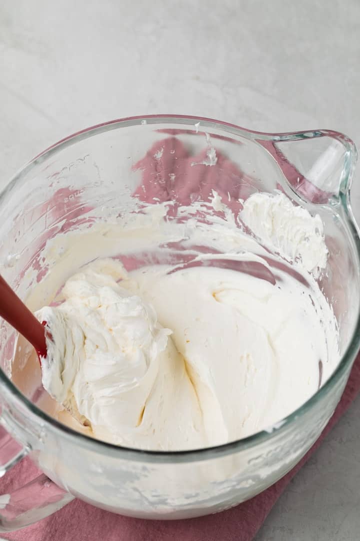 swiss meringue buttercream in a glass mixing bowl with red spatula