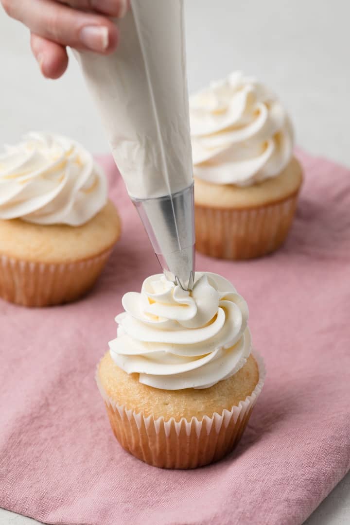 piping swiss meringue buttercream on cupcakes