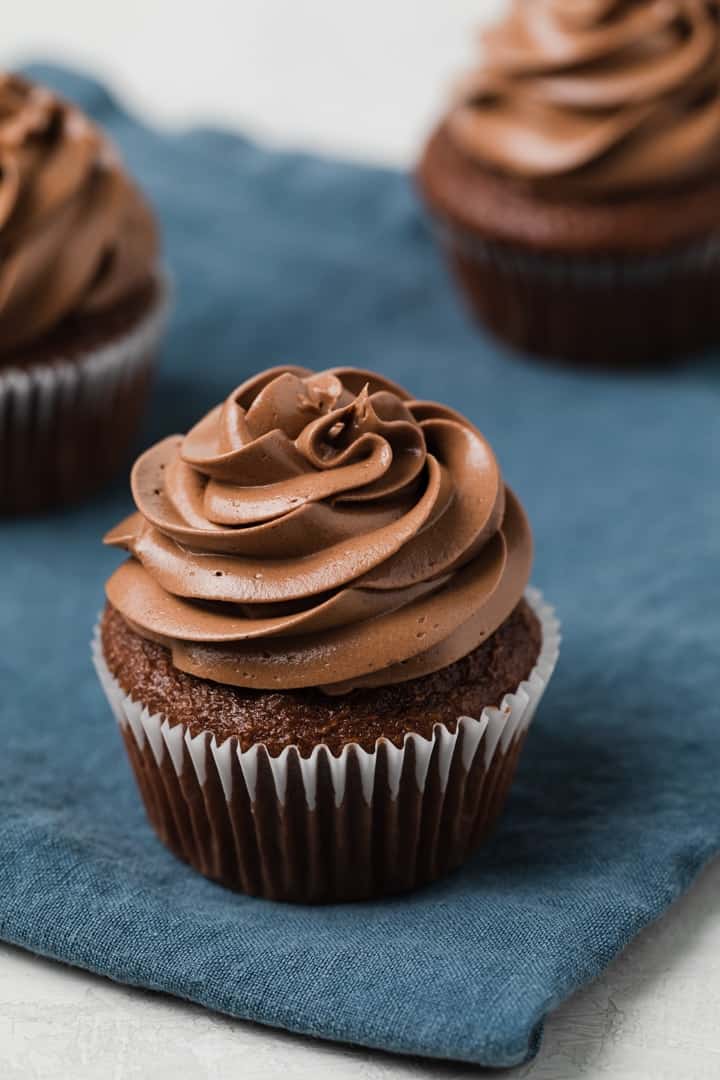 silky swirls of chocolate Swiss meringue frosting on top of chocolate cupcakes