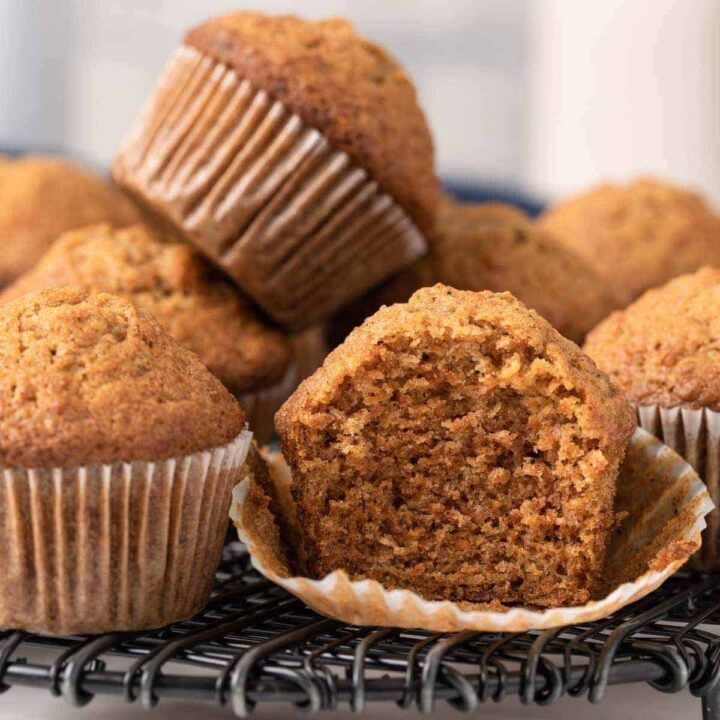 A stack of carrot muffins and one has a bite taken out.