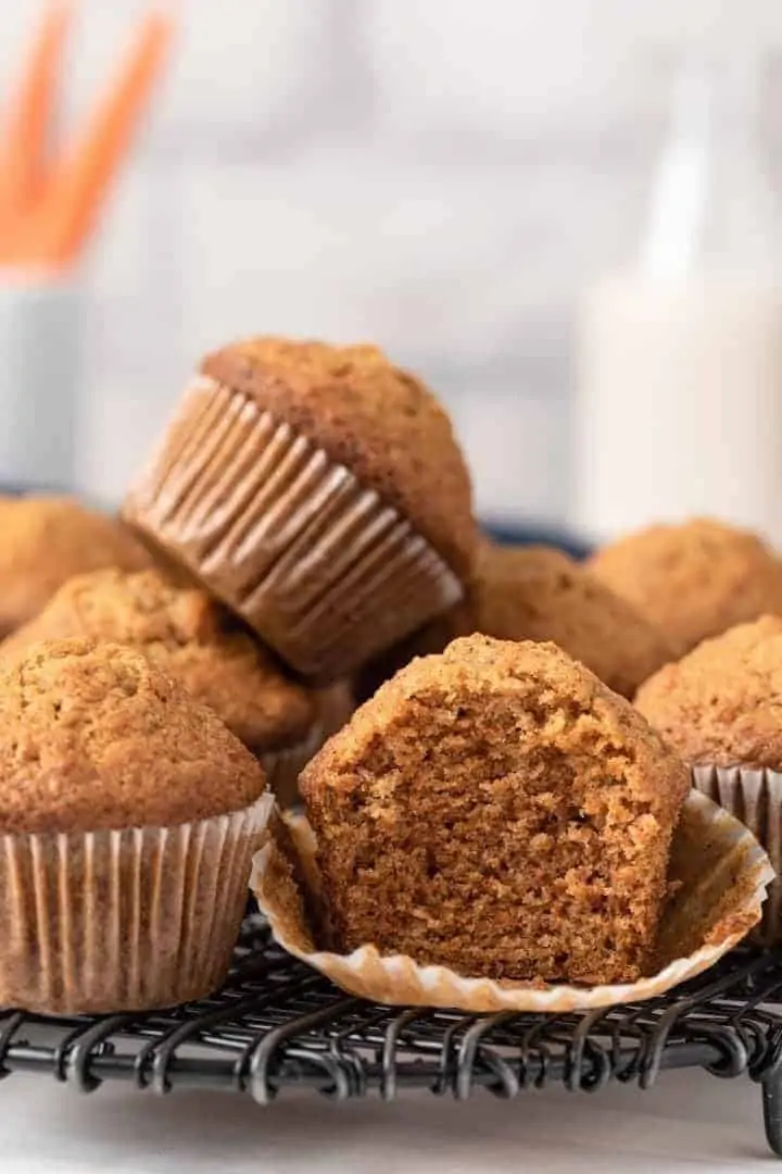 A stack of carrot muffins and one has a bite taken out.