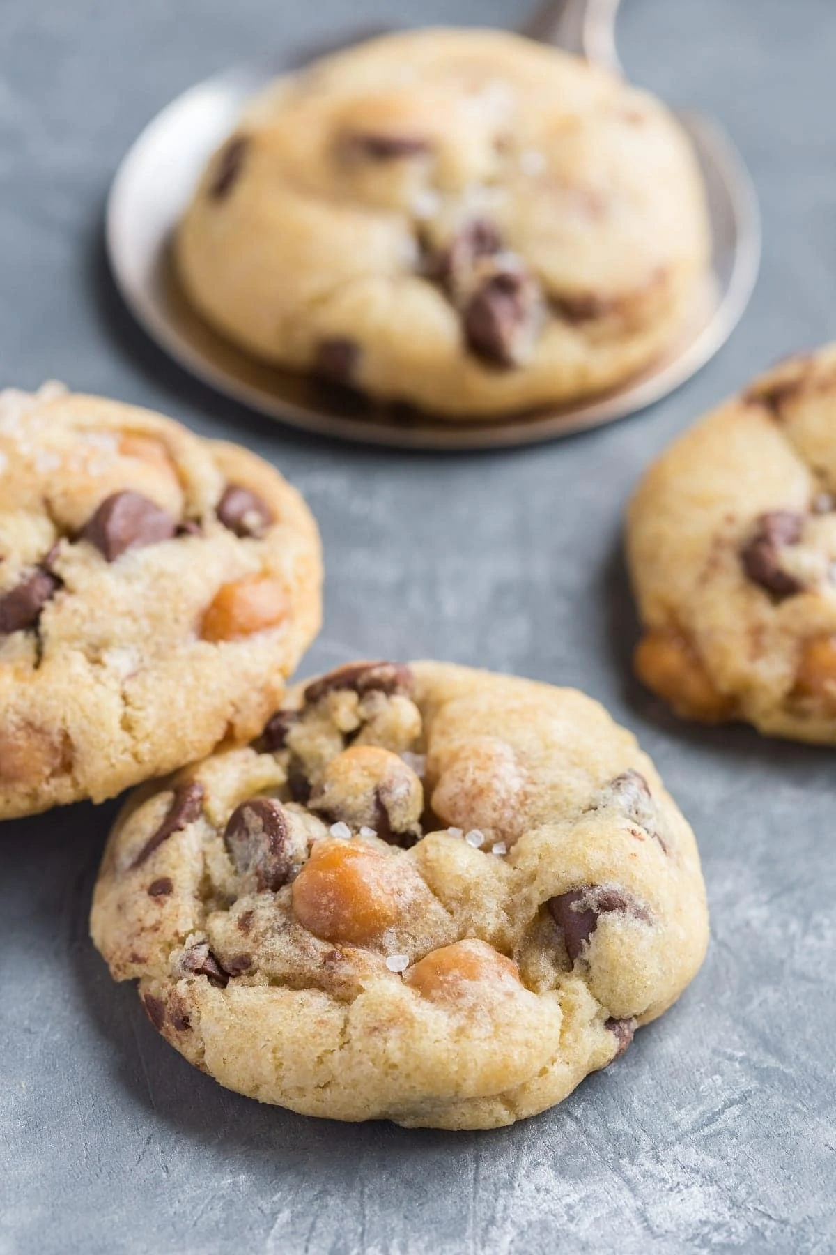 Side view of Chocolate Chip Salted Caramel Cookies on a grayish blue background.