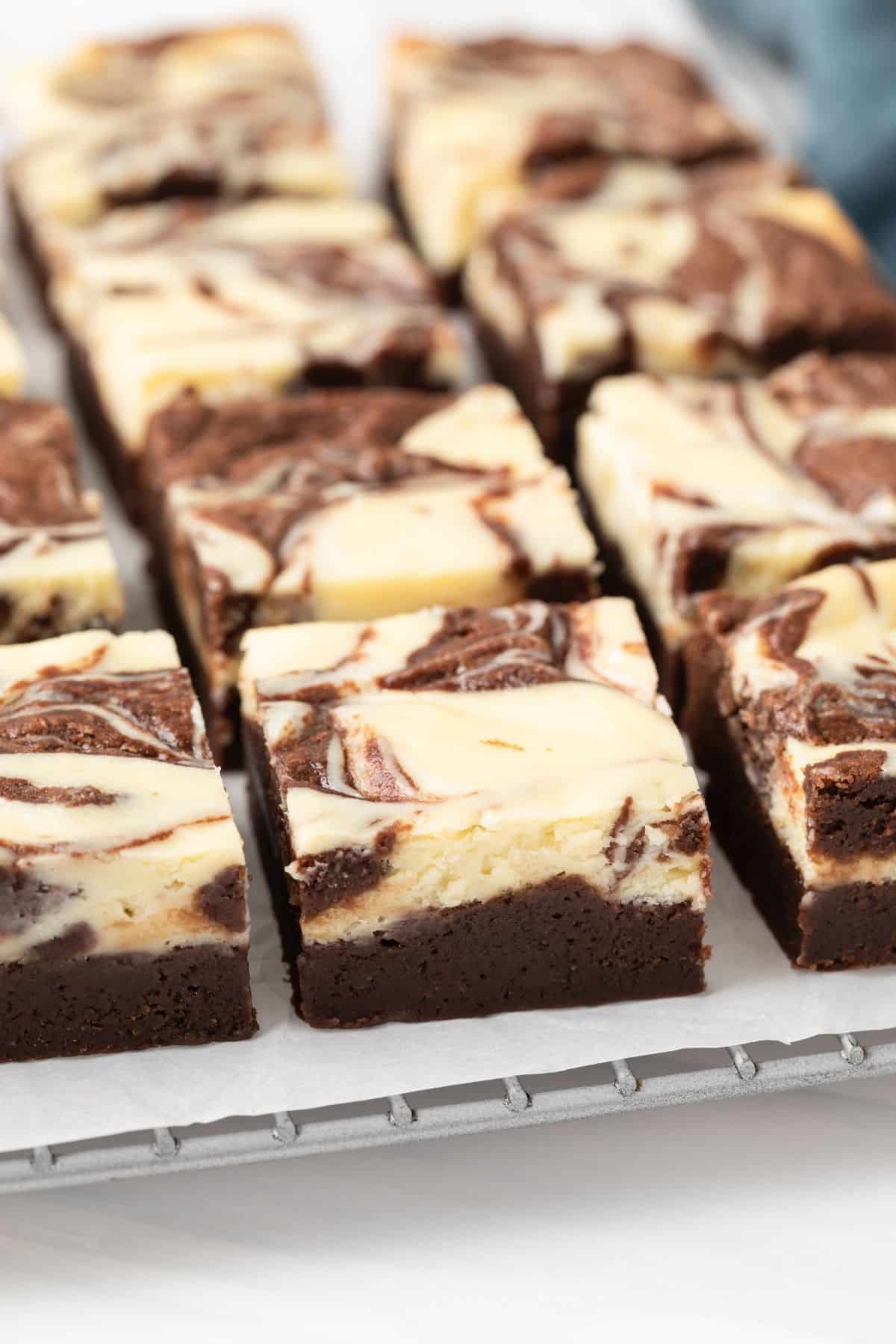 Close up of fudgy cheesecake brownies on a wire rack.