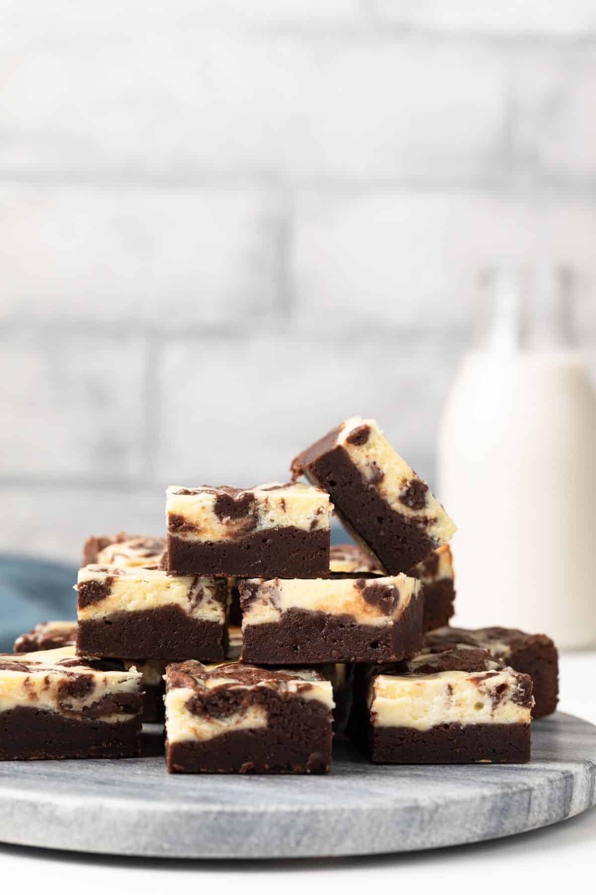 Cheesecake brownies stacked on a grey marbled platter.