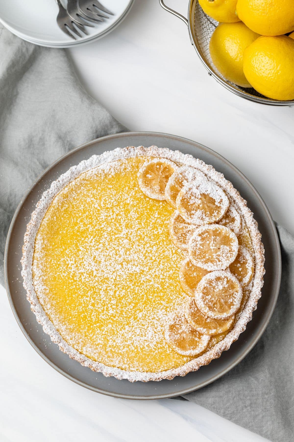 Overhead of lemon curd tart garnished with lemon slices and powdered sugar.