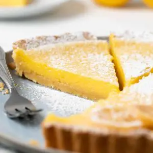 Side view of slice of lemon tart on a plate with fork.