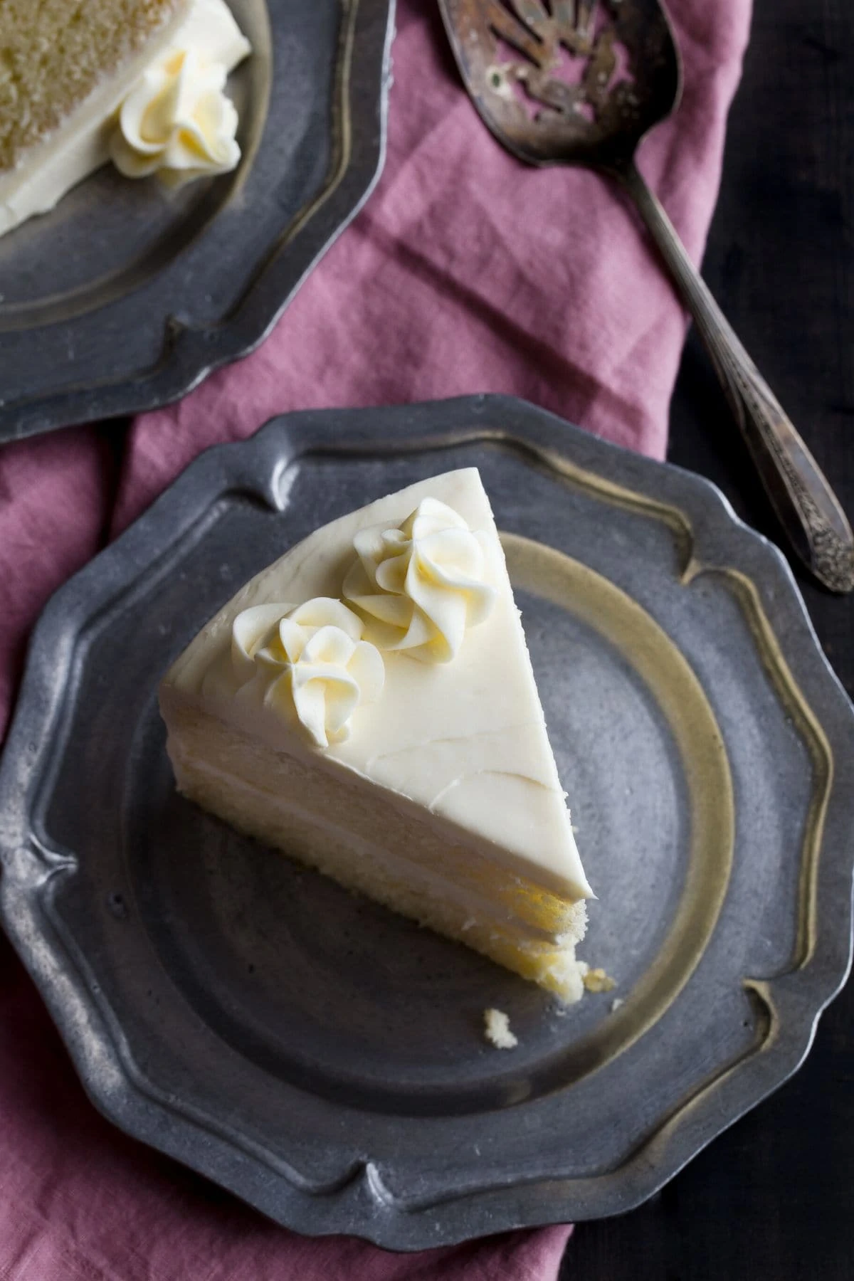 Overhead view of a slice of vanilla cake on a pewter plate.
