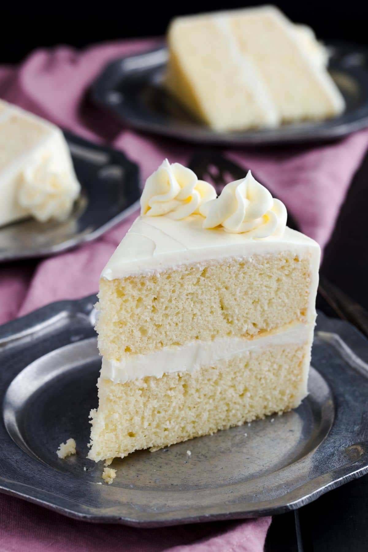 Side view of slice of vanilla cake with vanilla frosting.