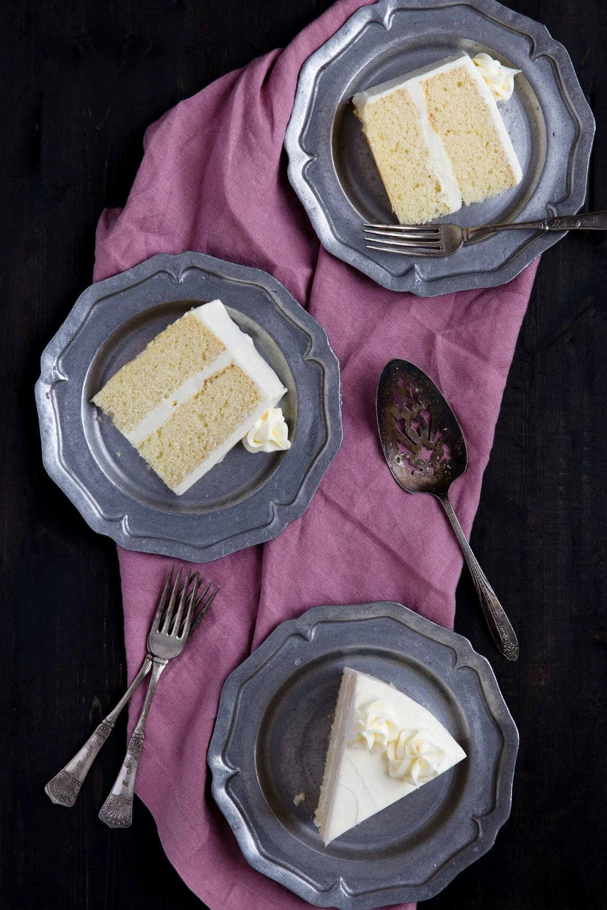 Three pewter plates with a slice of basic vanilla cake on each one.