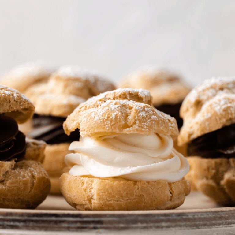 Side view of cream puffs filled with whipped cream and dusted with powdered sugar.