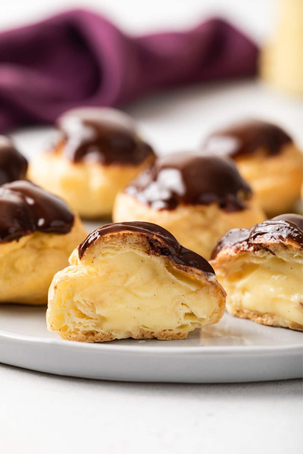 Chocolate glazed profiterole cut open so the filling is visible.