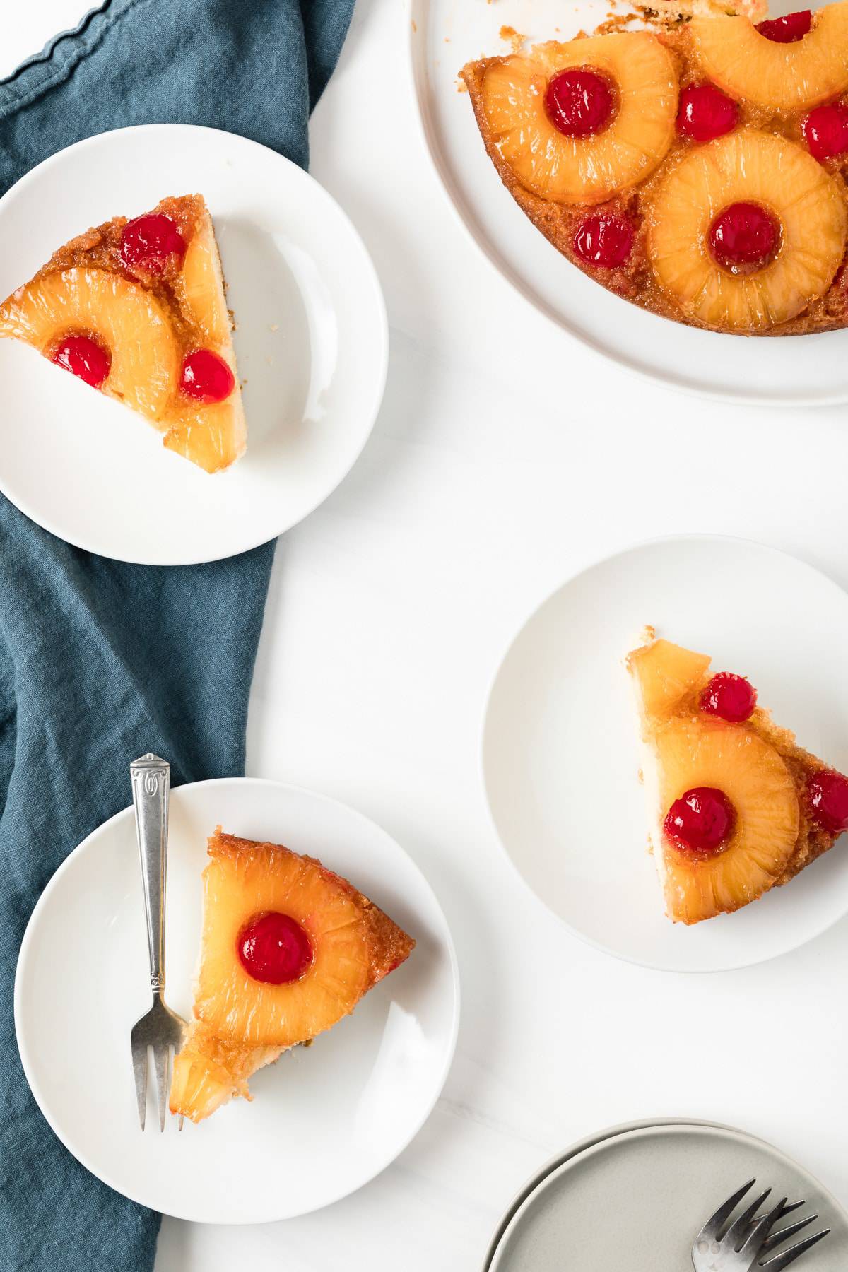 three slices of classic pineapple upside-down cake on white plates