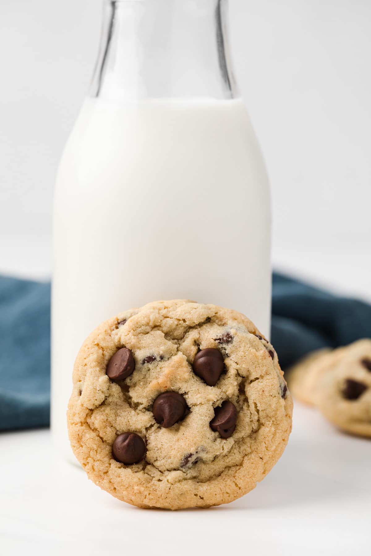 chocolate chip cookie leaning against glass jar of milk