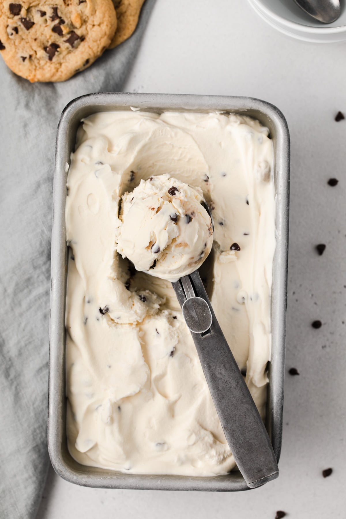 overhead of scoop filled with cookie dough ice cream laid across ice cream in loaf pan