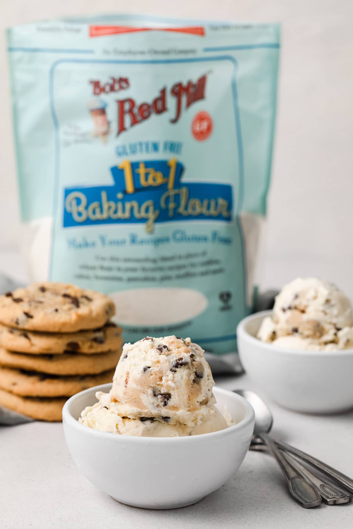 gluten free cookie dough ice cream in white bowl next to stack of chocolate chip cookies and Bob's Red Mill Gluten Free Flour