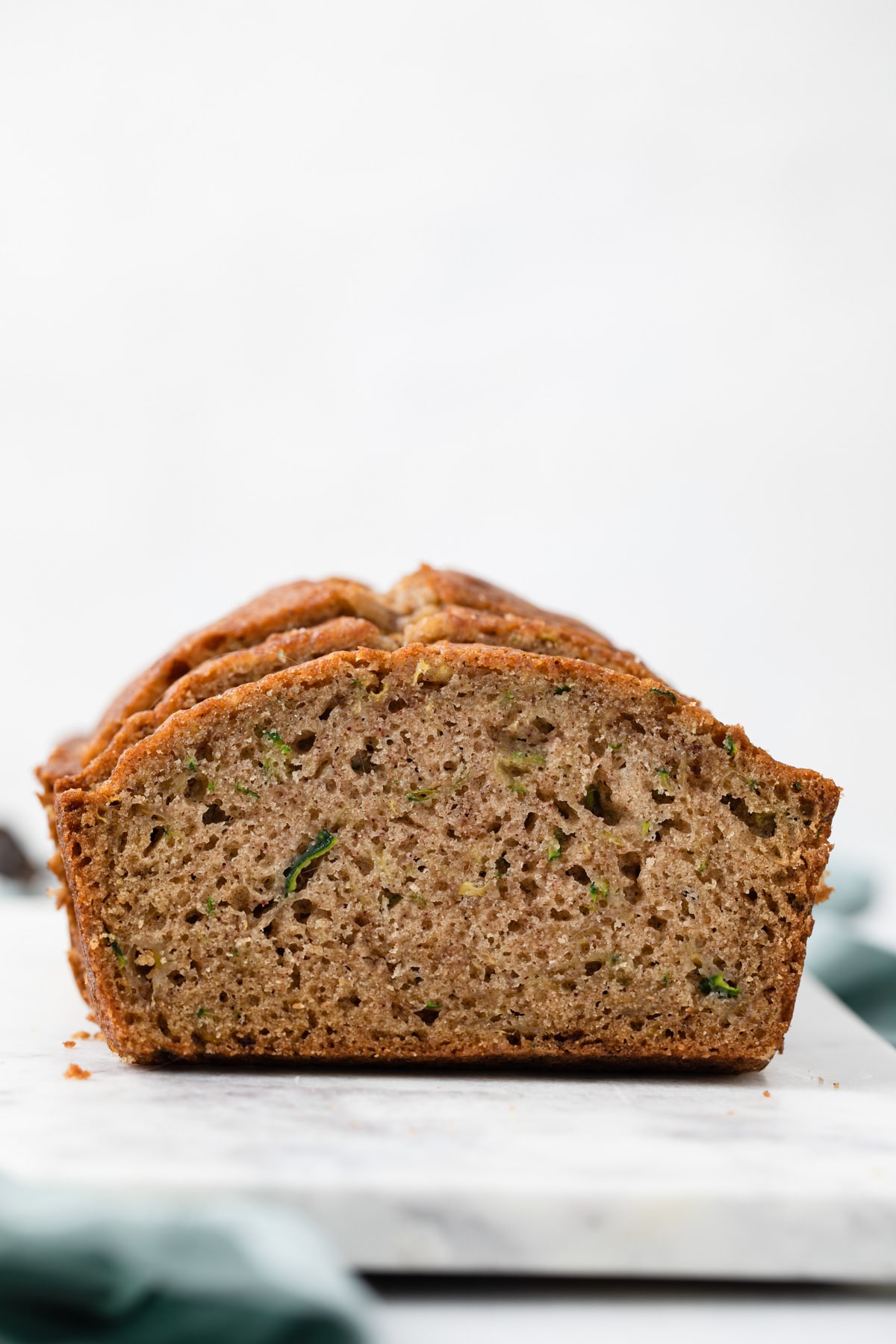 side view of open face zucchini bread on marble cutting board