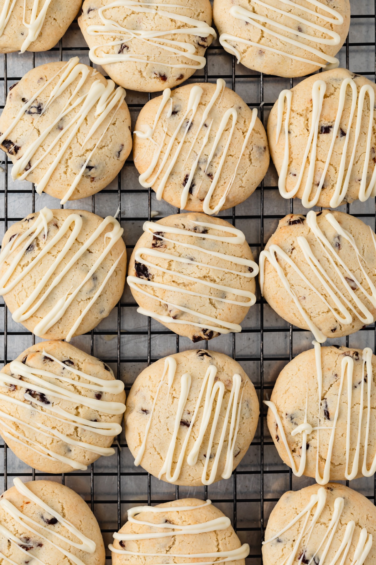 overhead view of cherry almond cookies with white chocolate drizzle on a wire rack