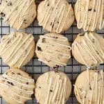 overhead view of cherry almond cookies with white chocolate drizzle on a wire rack