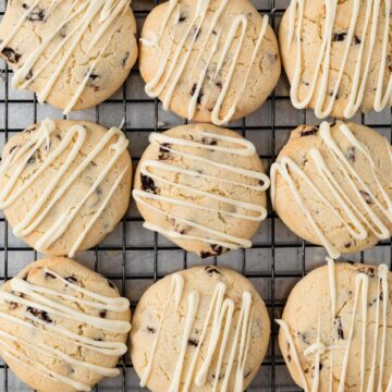 overhead view of cherry almond cookies with white chocolate drizzle on a wire rack