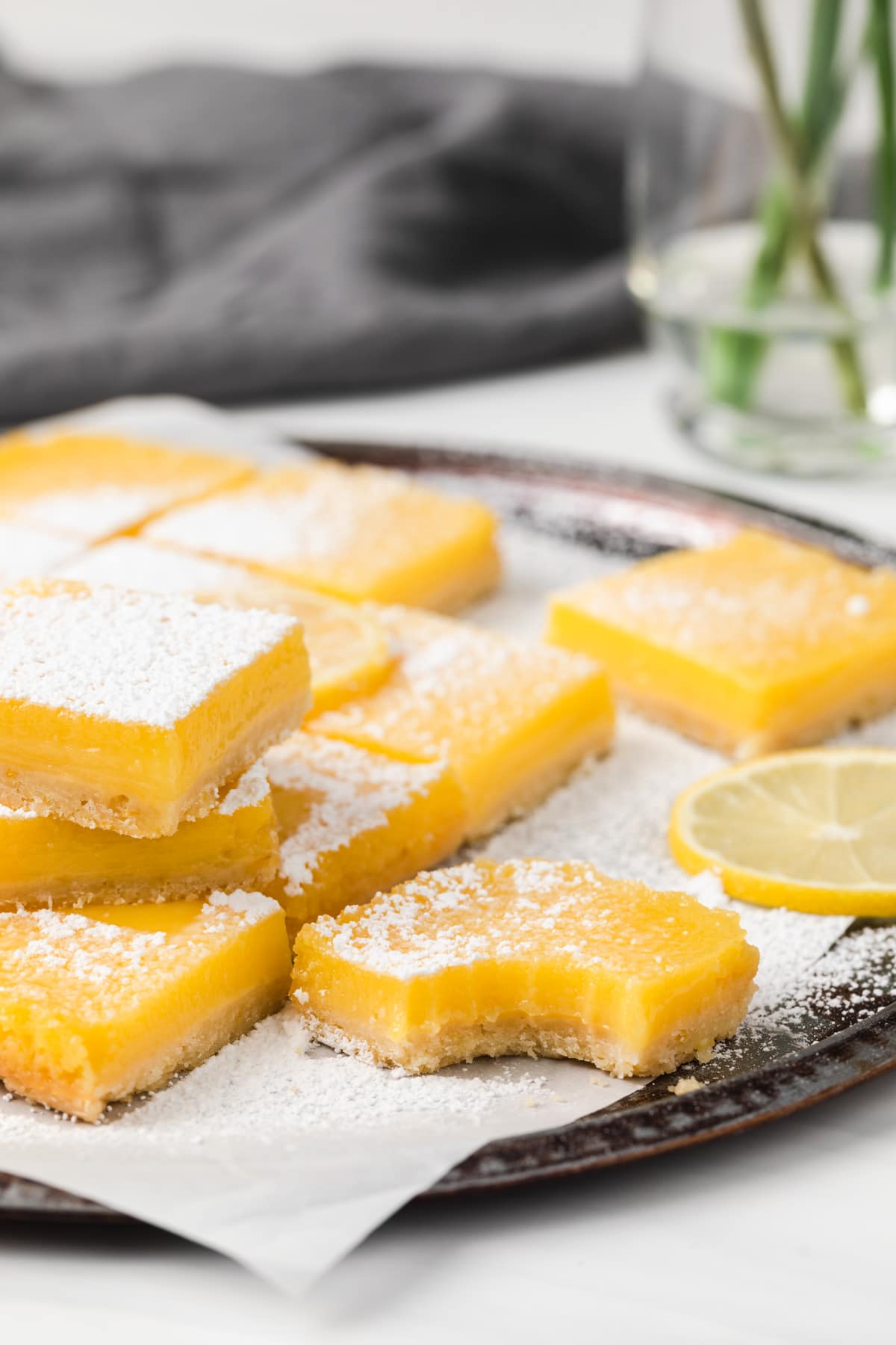 lemon bars on a parchment lined baking tray with a bite taken out of one