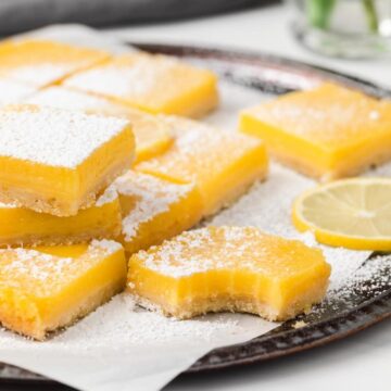 lemon bars on a parchment lined baking tray with a bite taken out of one