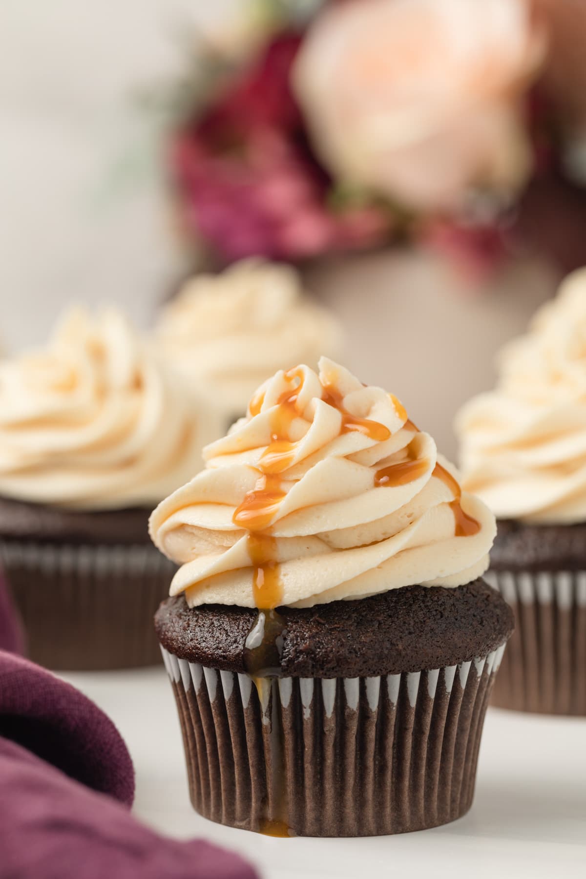 salted caramel frosting swirled on top of a chocolate cupcake with a drizzle of caramel sauce