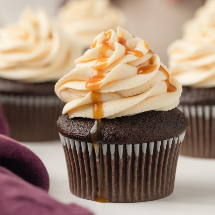 salted caramel frosting swirled on top of a chocolate cupcake with a drizzle of caramel sauce