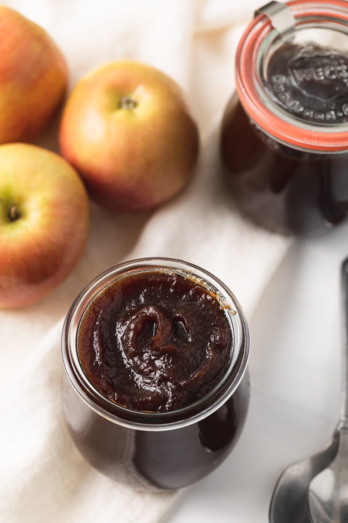 high angled view of apple butter in glass jar with apple and jar of apple butter behind it