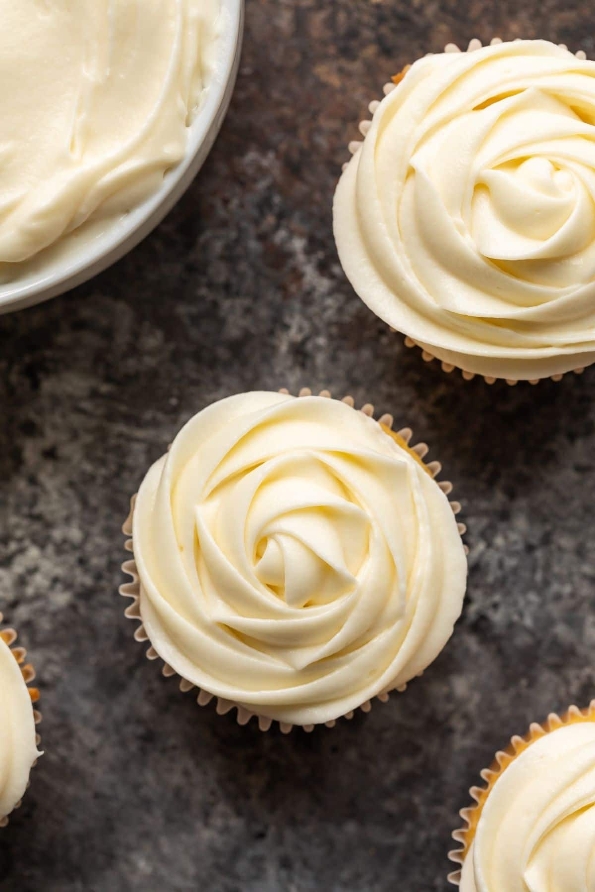 Close up overhead view of cream cheese frosting swirled over yellow cupcakes