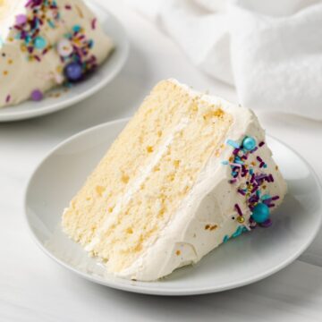 side view of slice of moist vanilla cake with colorful sprinkles on white plate