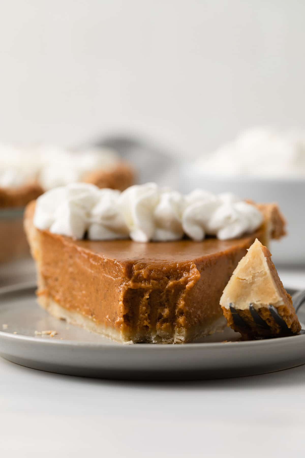 front view of pumpkin pie slice with bite taken out on fork