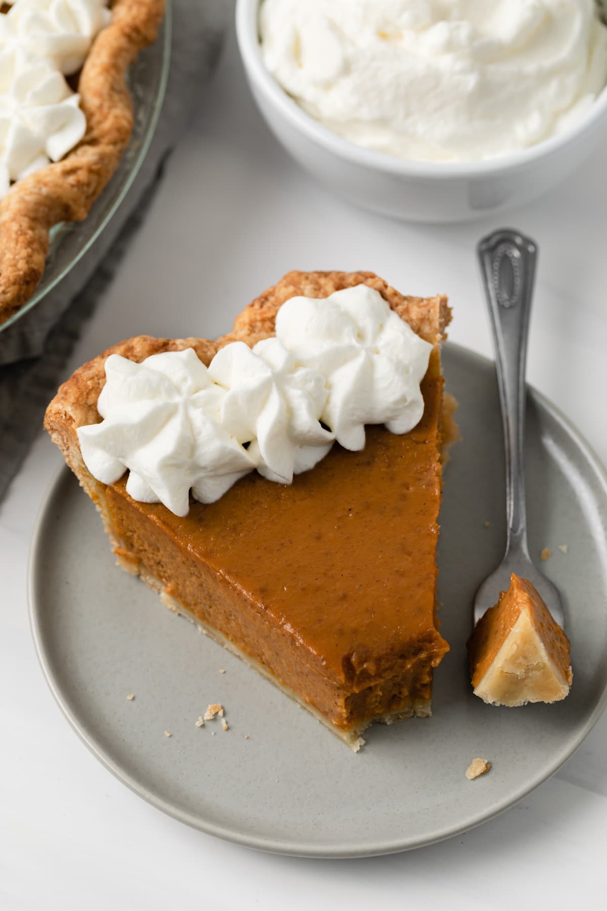 high angled view of pumpkin pie slice on plate with fork taking bite out