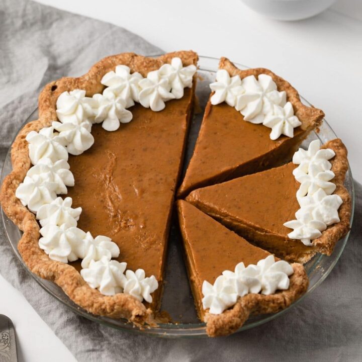 angled view of pumpkin pie with slices cut