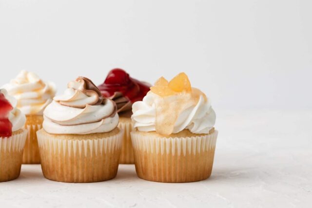 five cupcakes with various frostings staggered to left of image