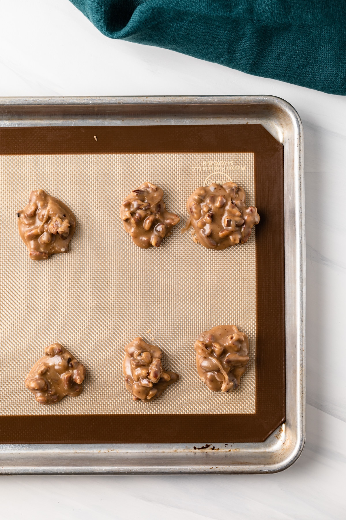 overhead of praline pecans on baking sheet with silicone mat