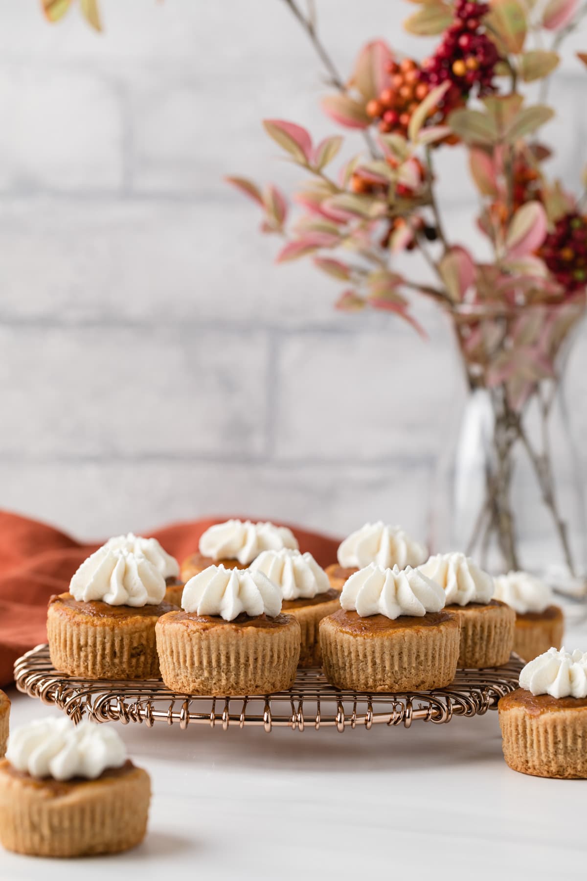 side view of mini pumpkin pies topped with whipped cream on a round wire rack