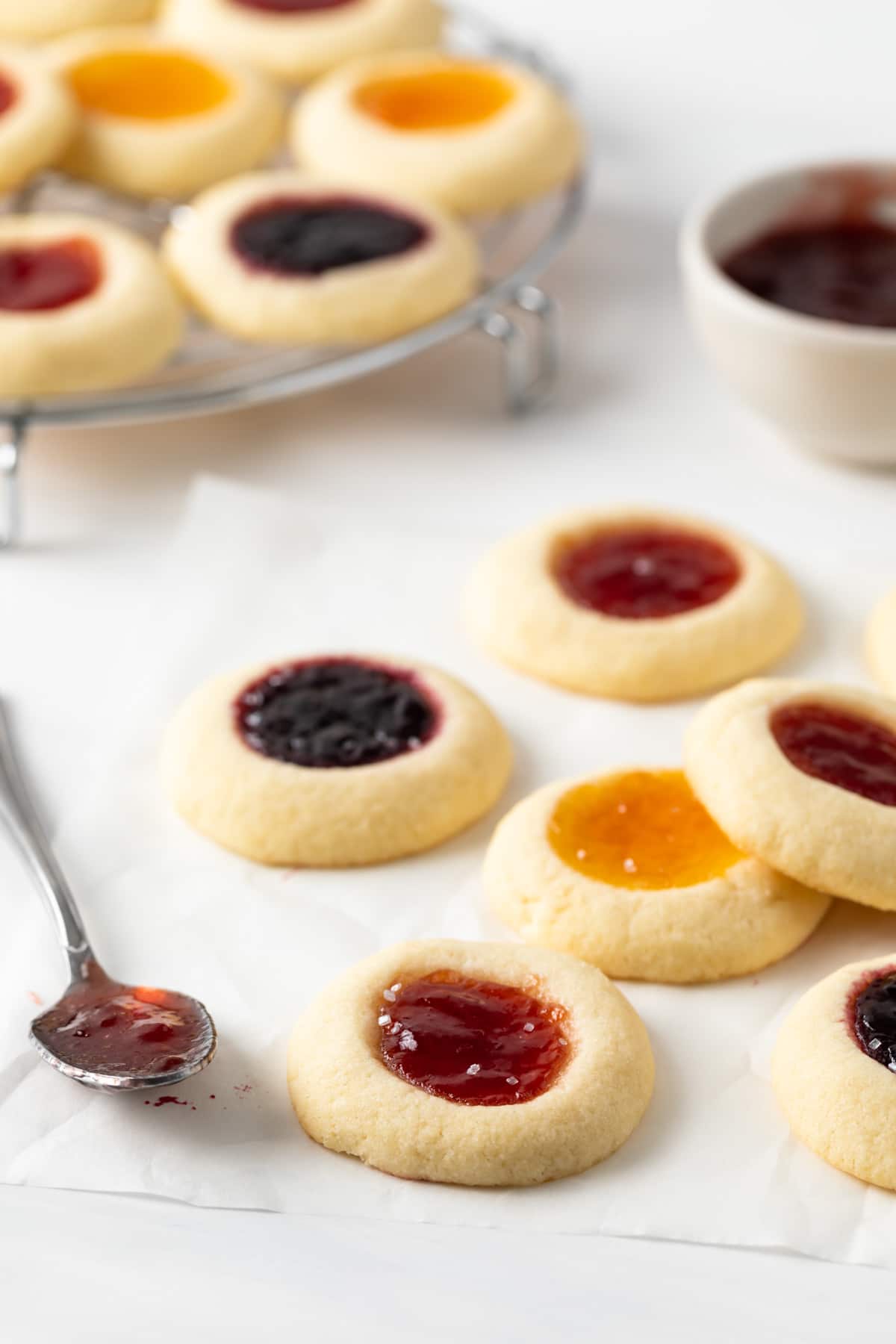 angled view of jam thumbprint cookies on white parchment paper