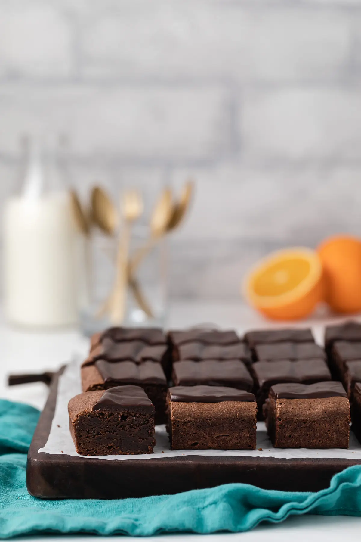 chocolate orange brownies with chocolate glaze on wood board lined with parchment paper