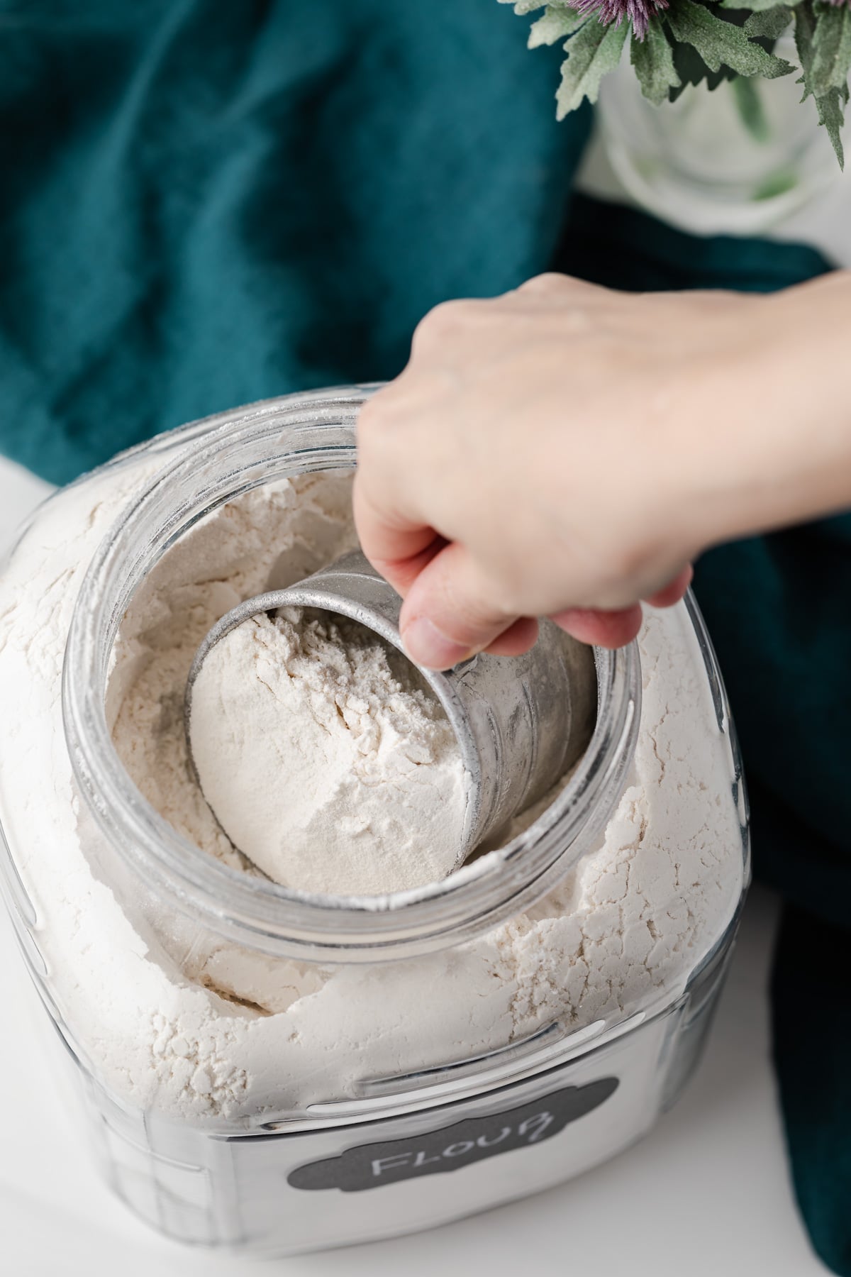 scooping flour from jar with measuring cup