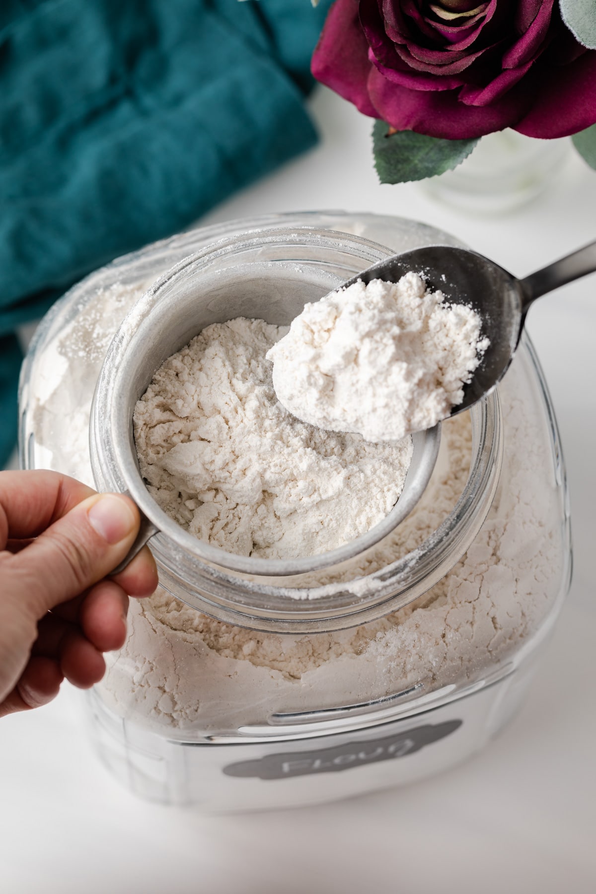 spooning flour from jar into measuring cup