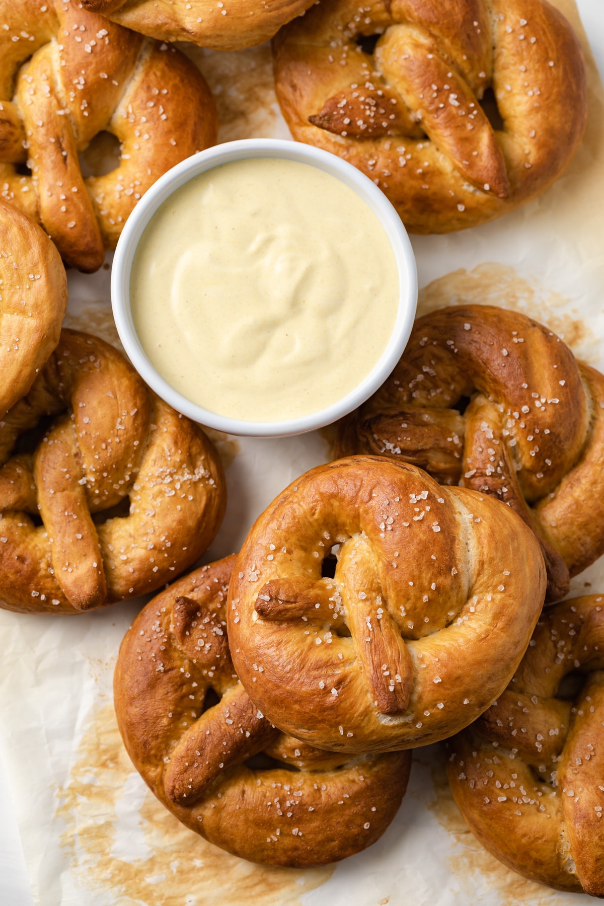 overhead of soft pretzels on a baking sheet with white bowl of mustard sauce