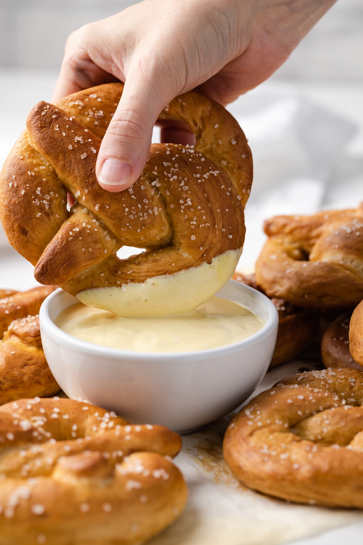 dipping soft pretzel in mustard sauce