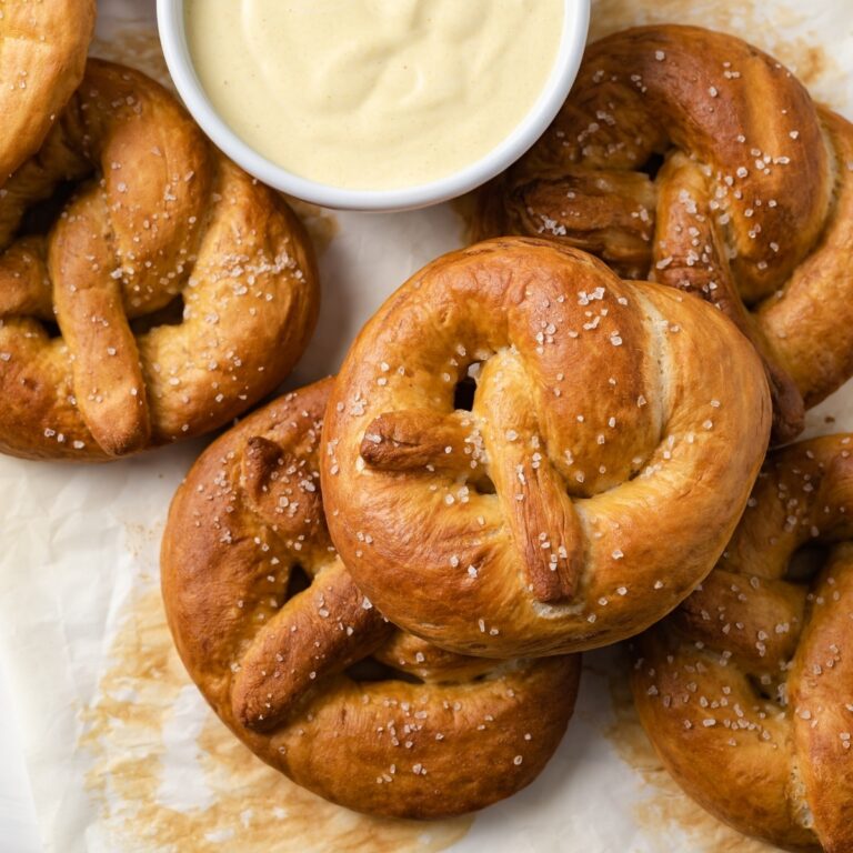 overhead of soft pretzels on a baking sheet with white bowl of mustard sauce