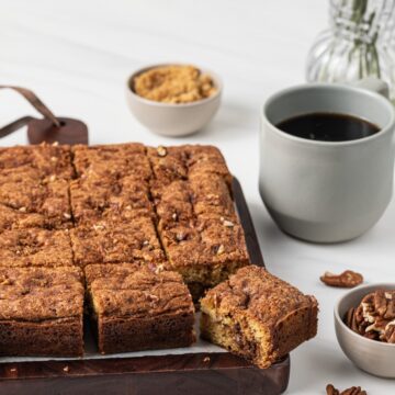 sliced coffee cake on wooden board with cup of coffee
