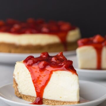 side view of slice of strawberry cheesecake on white plate