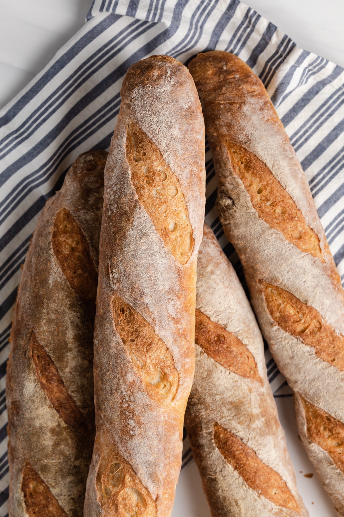 overhead of baguettes on a blue and white striped napkin