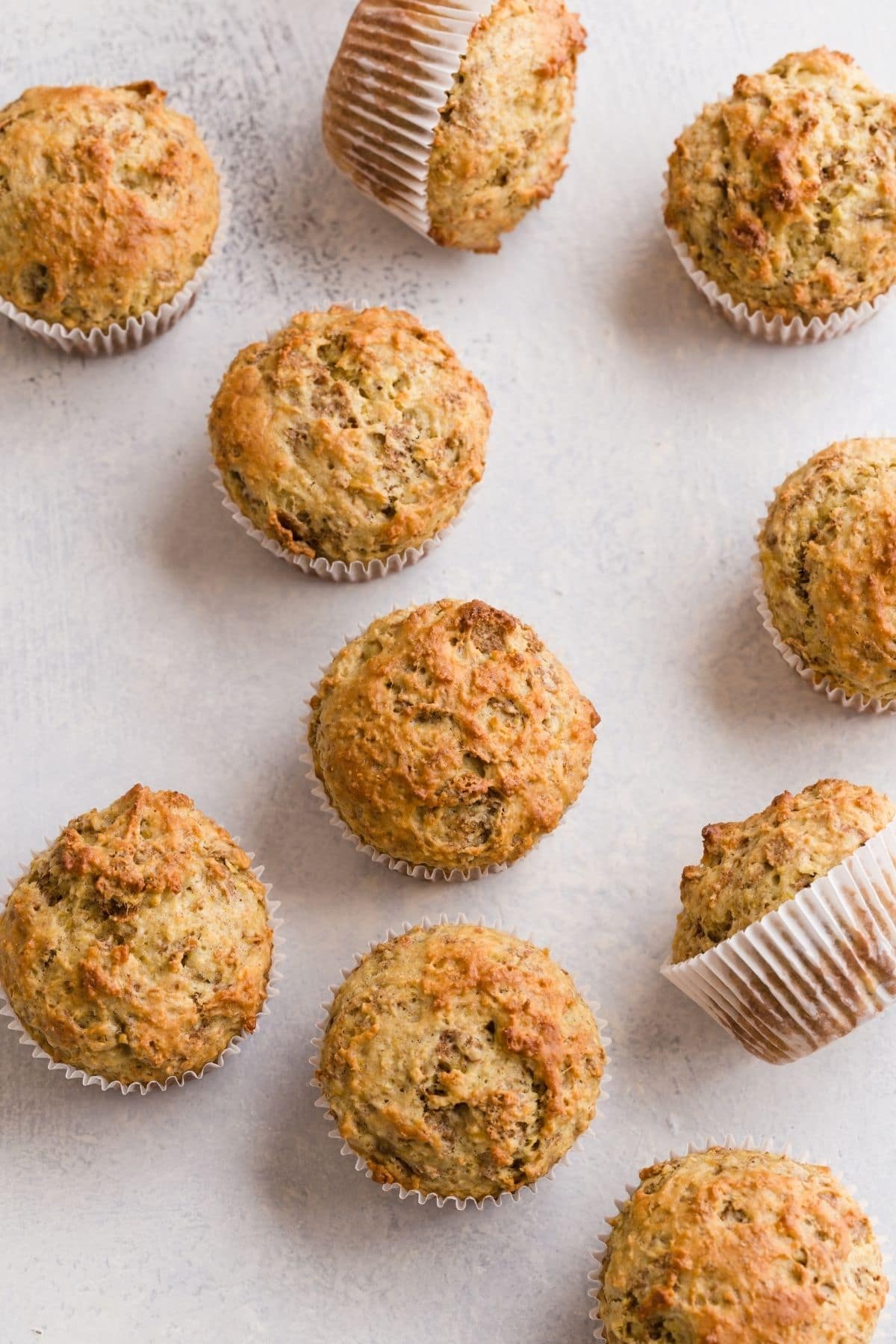 Banana Bran Muffins scattered on a white table top.