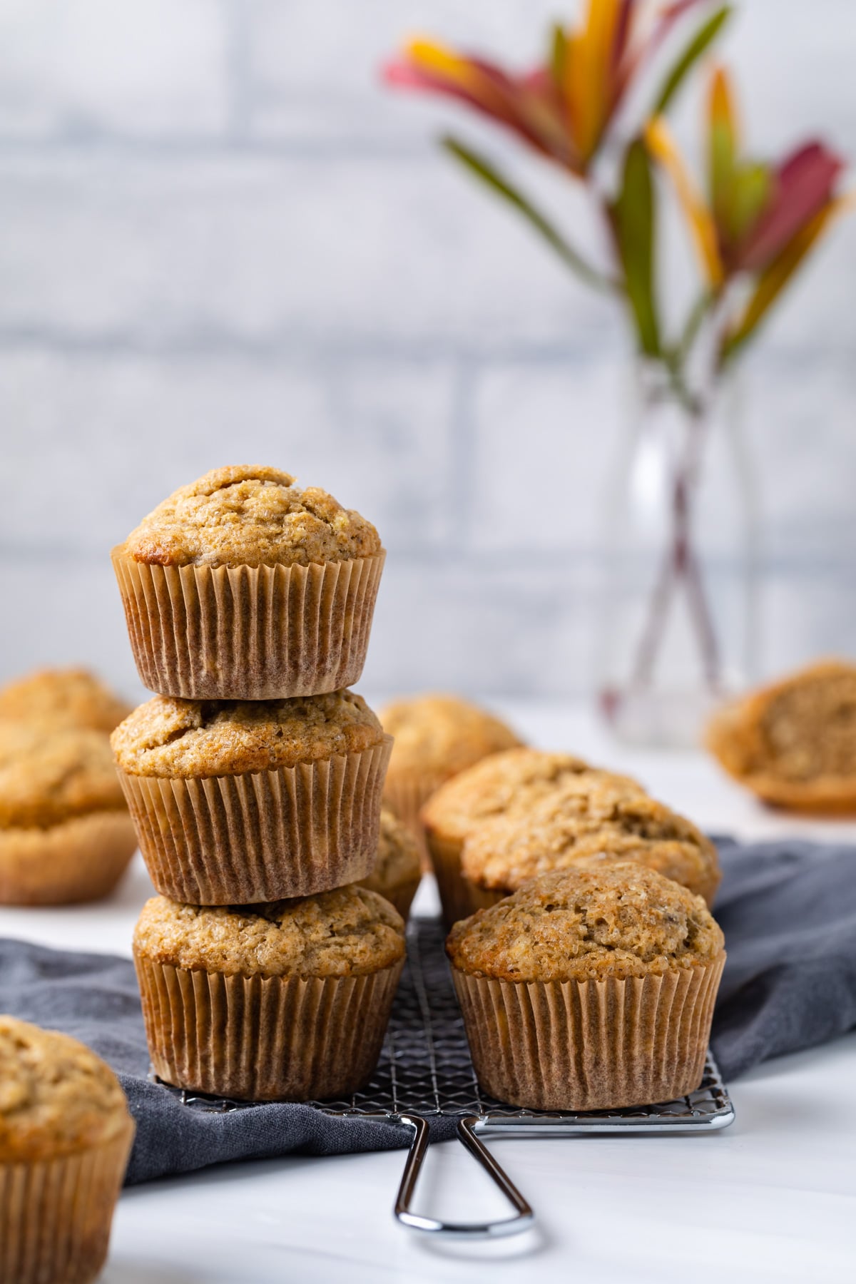 three banana muffins stacked with more sitting next to it
